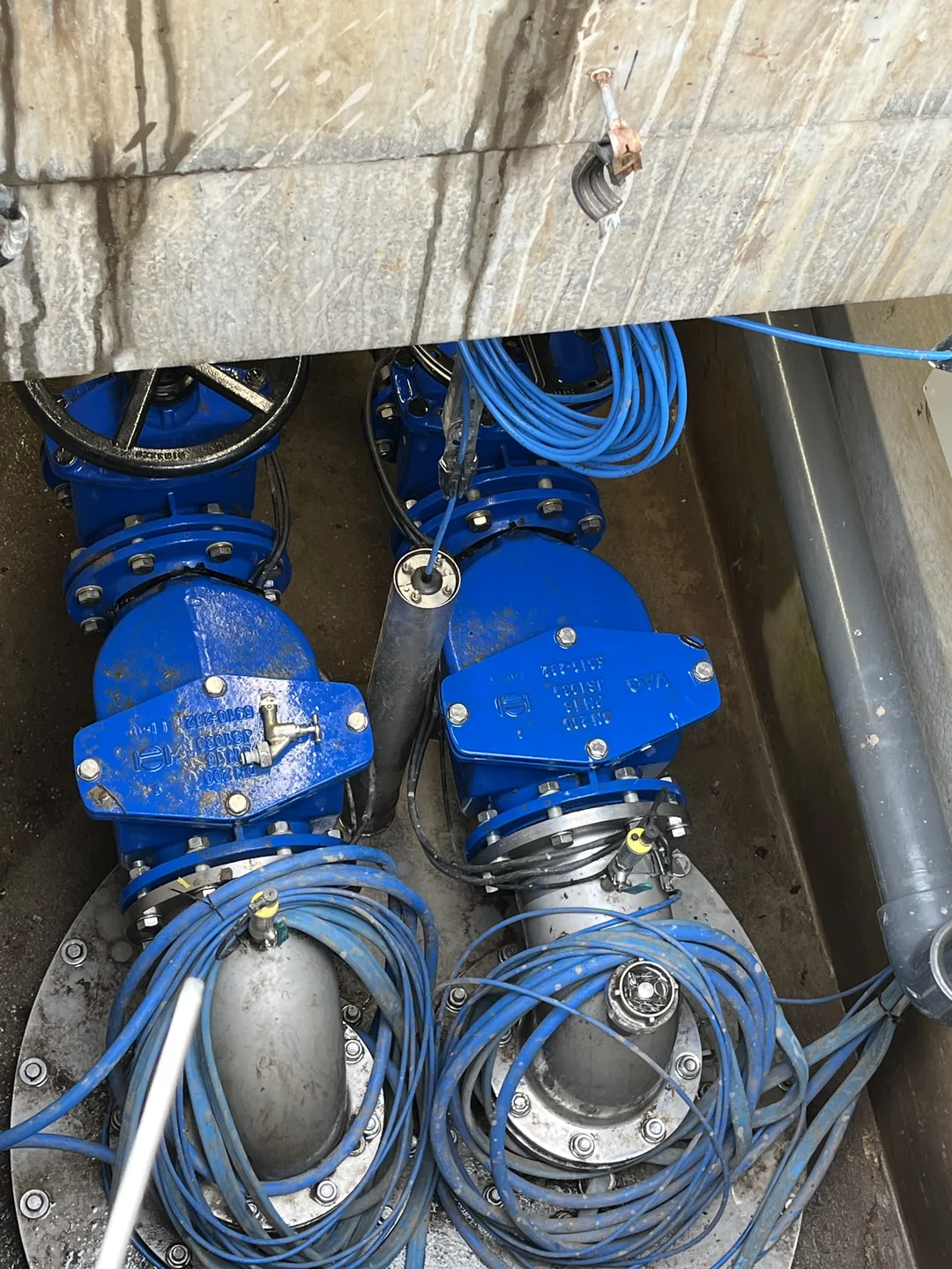 Blaue Armaturen, Sonden und Kabel in einem Brunnenschacht.