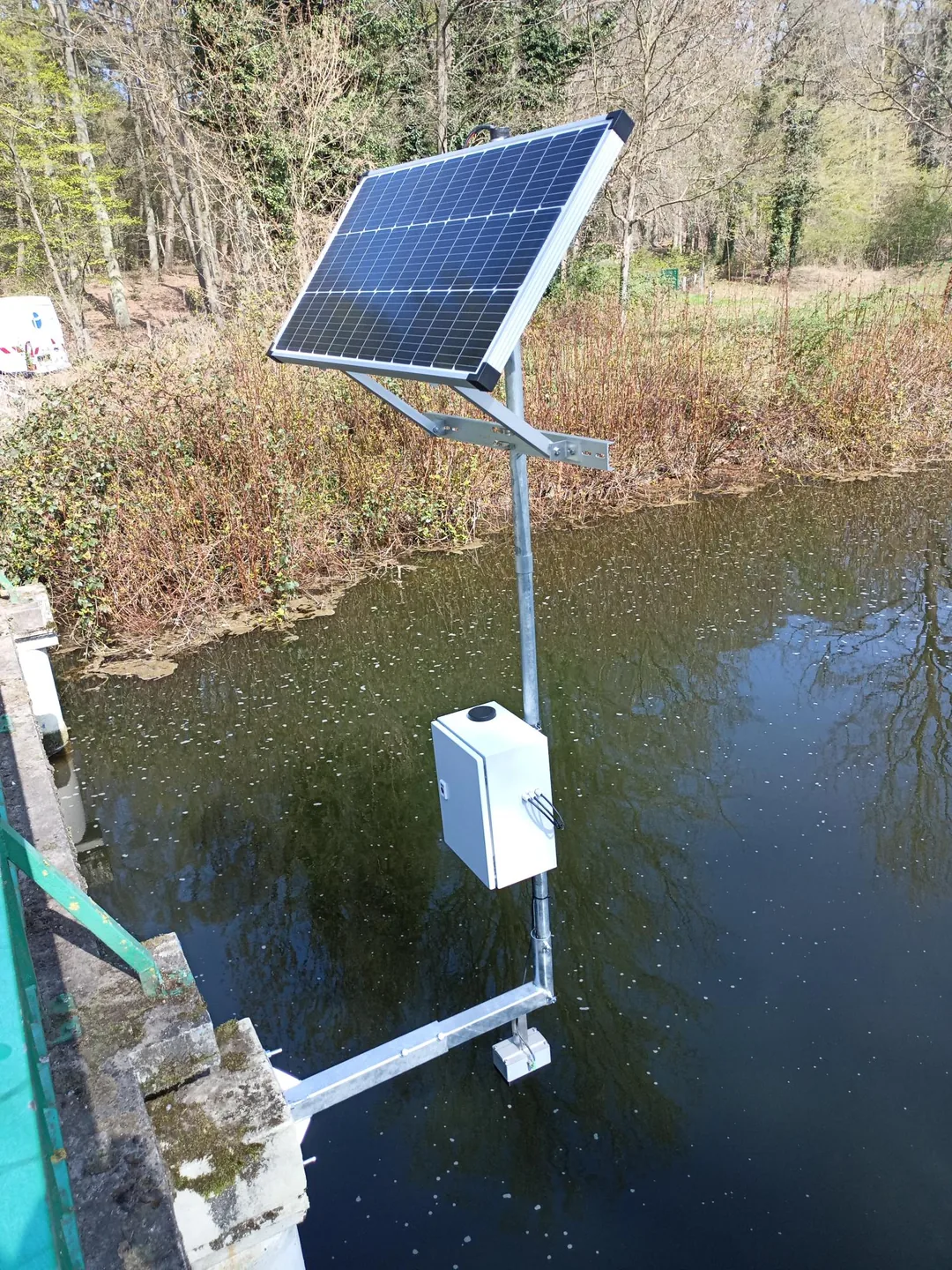 Solarversorgte Messstation mit Schaltschrank und Sensorträger an einer Brücke.
