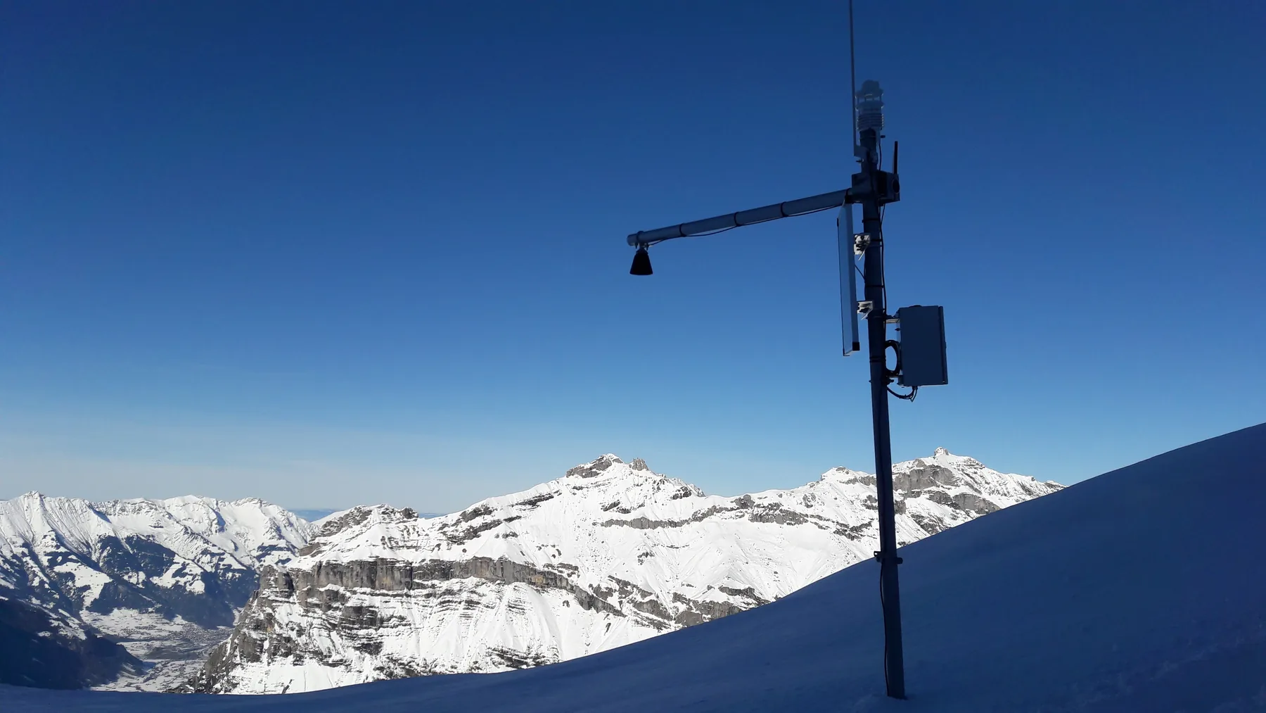 Wetterstation vor schneebedecktem Alpenpanorama am Wildstrubel.