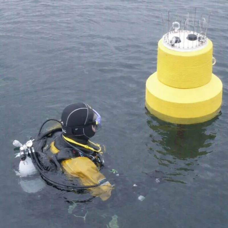 Taucher neben einer gelben Messboje im Wasser.