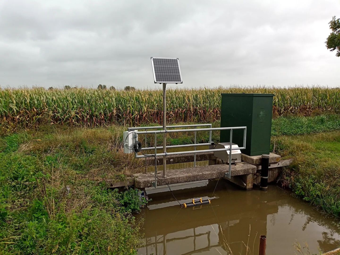 Monitoring station with a solar panel and floating sensor mount at a watercourse.