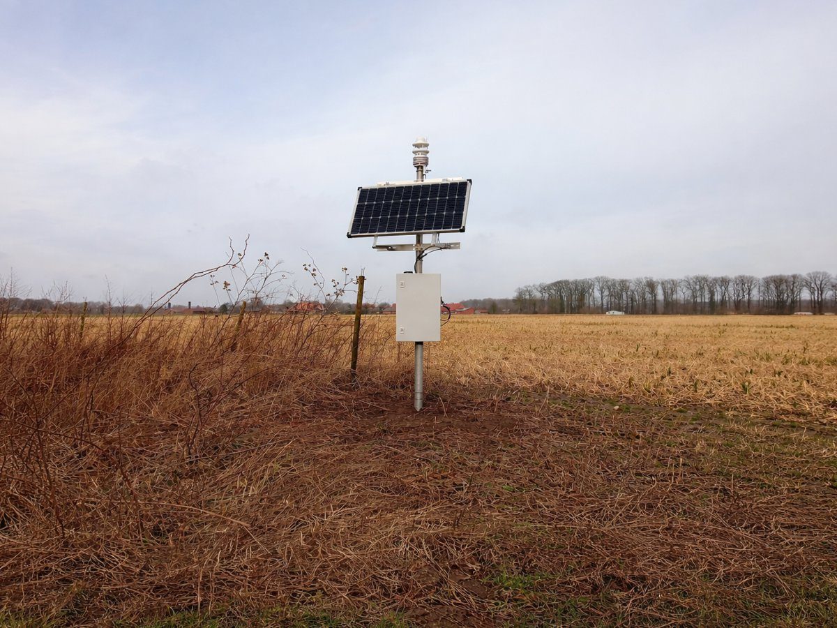 Klimastation mit Solarpanel und Wettergeber auf einem abgeernteten Acker im Spätwinter