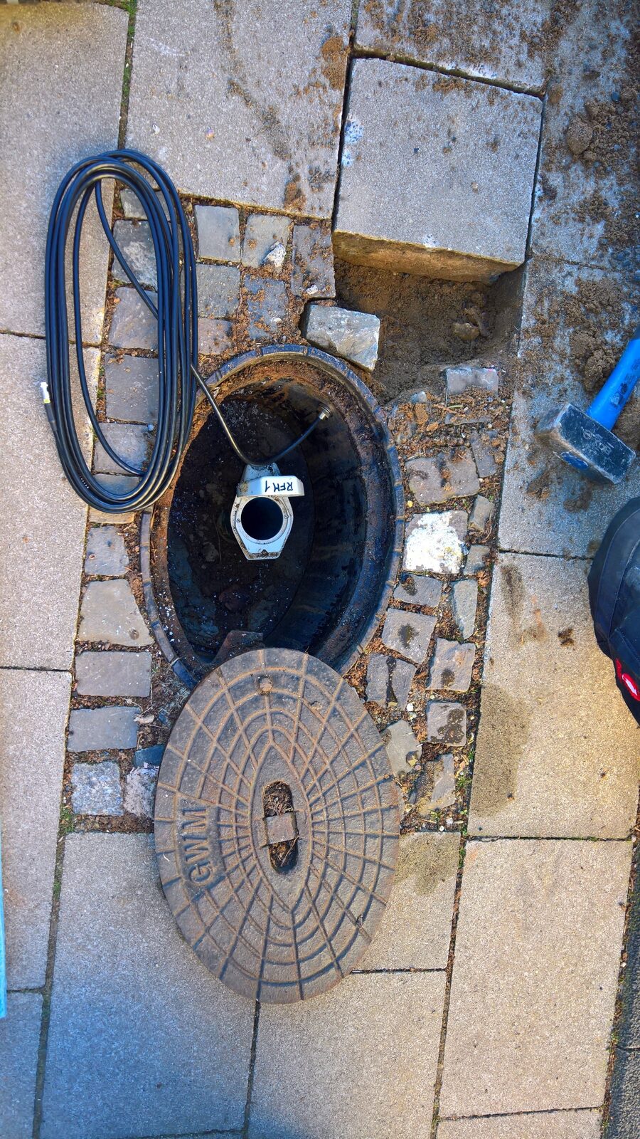 Geöffneter Pegelschacht bei der Inbetriebnahme, Sondenkabel und Schachtdeckel
