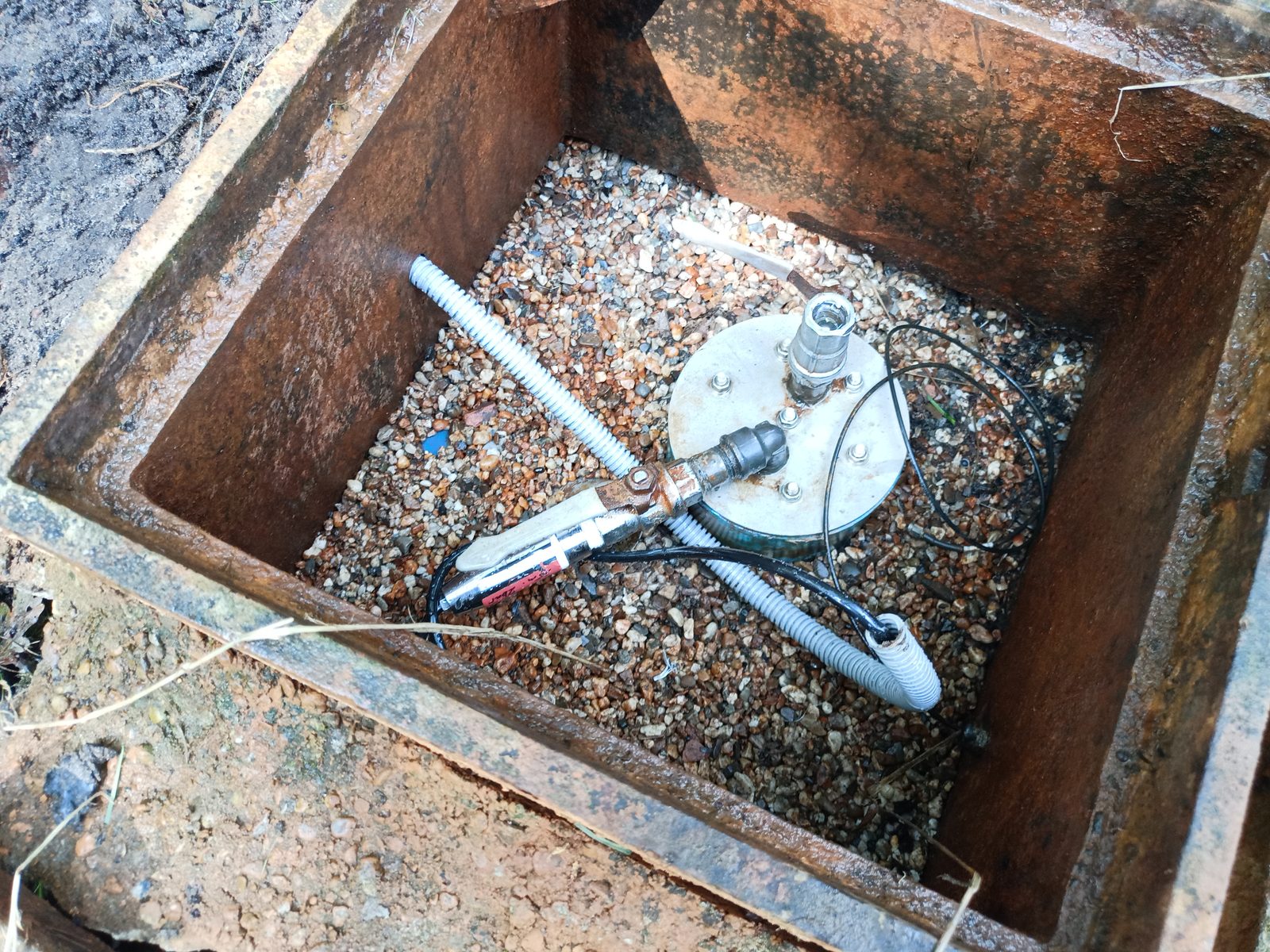 Sensorinstallation in geöffnetem Stahlkasten auf Kiesbett, Edelstahlplatte mit Kabelverschraubung
