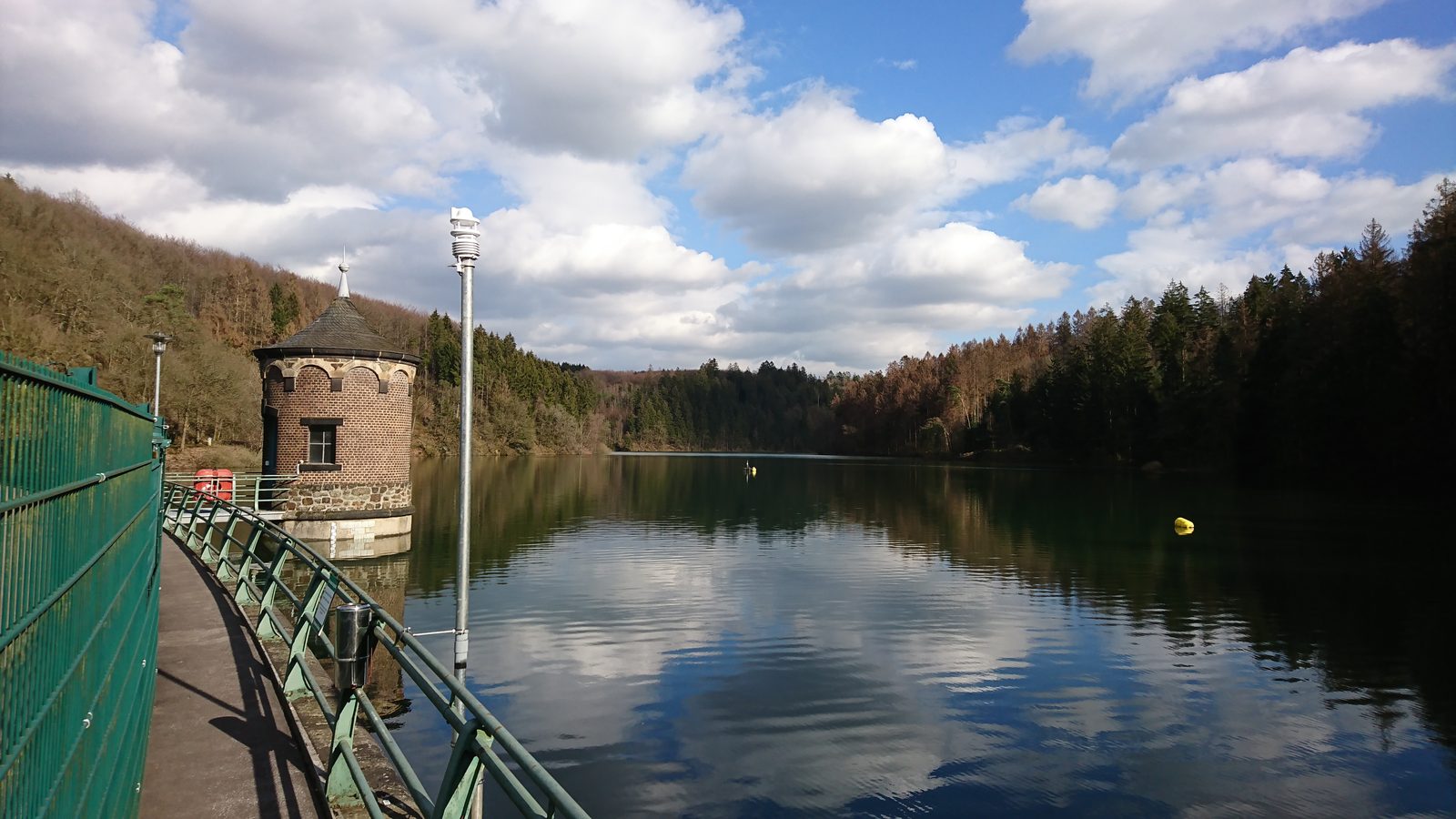 Talsperre mit historischer Bedienhütte am Mauerkronenweg, blauer Himmel über dem Stausee